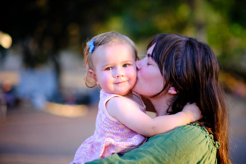 Mother kissing her baby's cheek in warm light