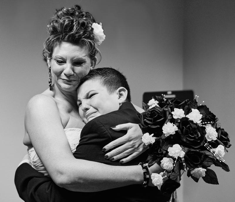 Bride embracing her tearful young son before the ceremony, black and white