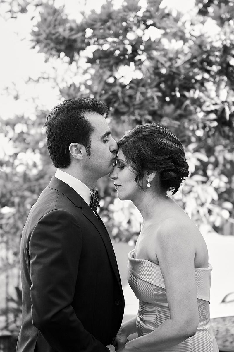 Groom kissing the bride on the forehead, black and white