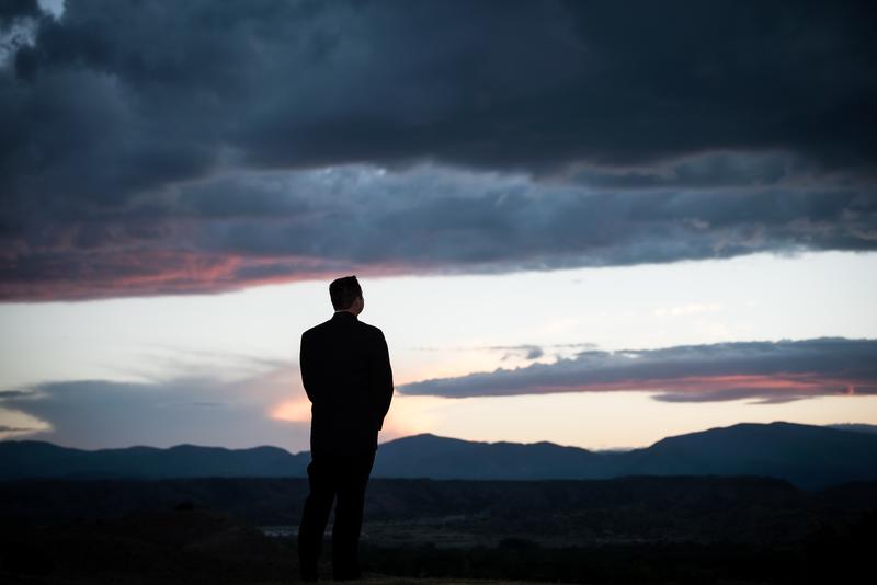 Groom silhouetted against a stormy sunset over the mountains