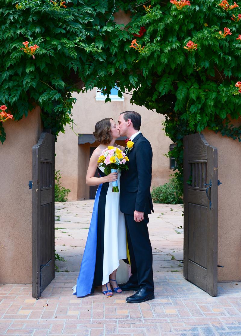 Couple kissing beneath trumpet vine in an open wooden gateway