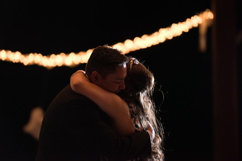 Couple embracing beneath string lights at night